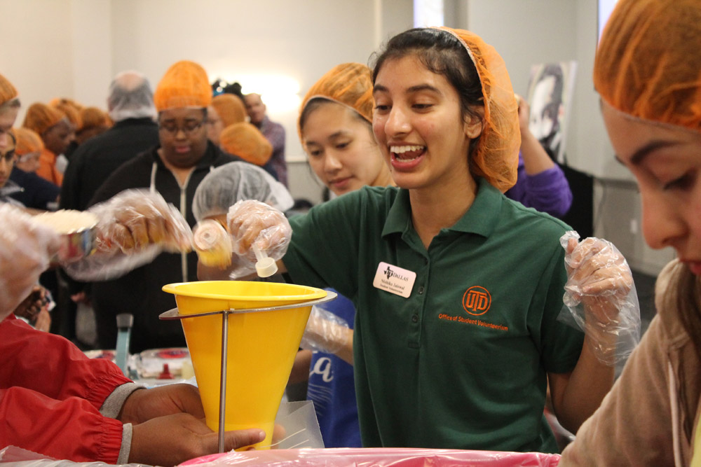 Neuroscience senior Nishika Jaiswal drops a measuring scoop of ingredients for prepackaged red lentil jambalaya meals that will be delivered to area children.