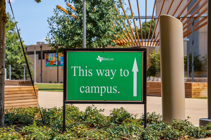 Outdoor sign with arrow reads, This way to campus.
