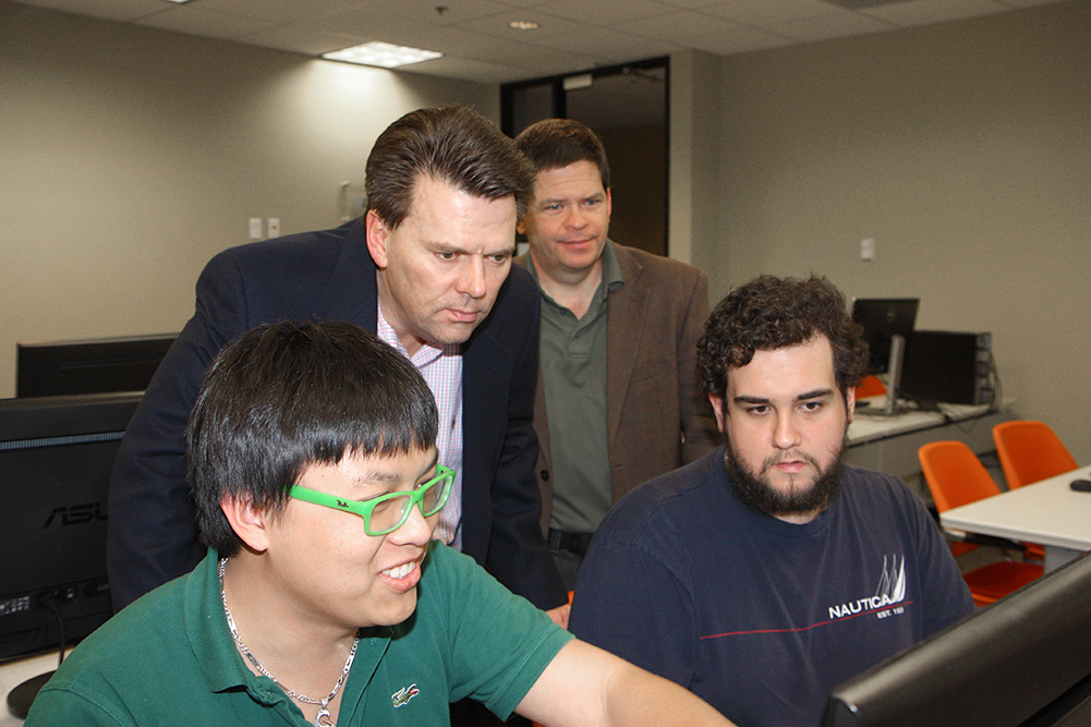 Patrick McCrane (left), Director of Tax Development, Intuit, and Rod Wetterskog, assistant dean for the Erik Jonsson School looks over the shoulders of students Vincent Thieu and Jerry Benavides, Computer Science UTDesign students.